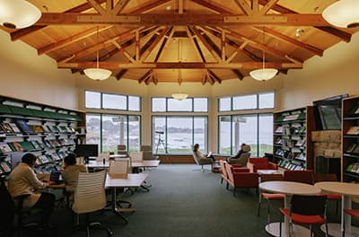 A library reading room with big picture windows looking out at the ocean.